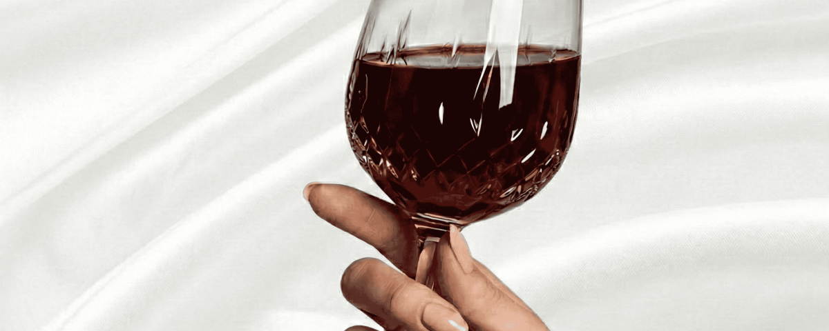 Manicured hand holding a decorative wine glass.